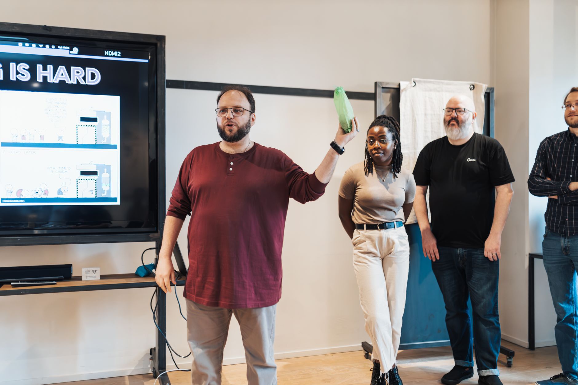 Diverse team presents in a modern office environment with a large screen display.