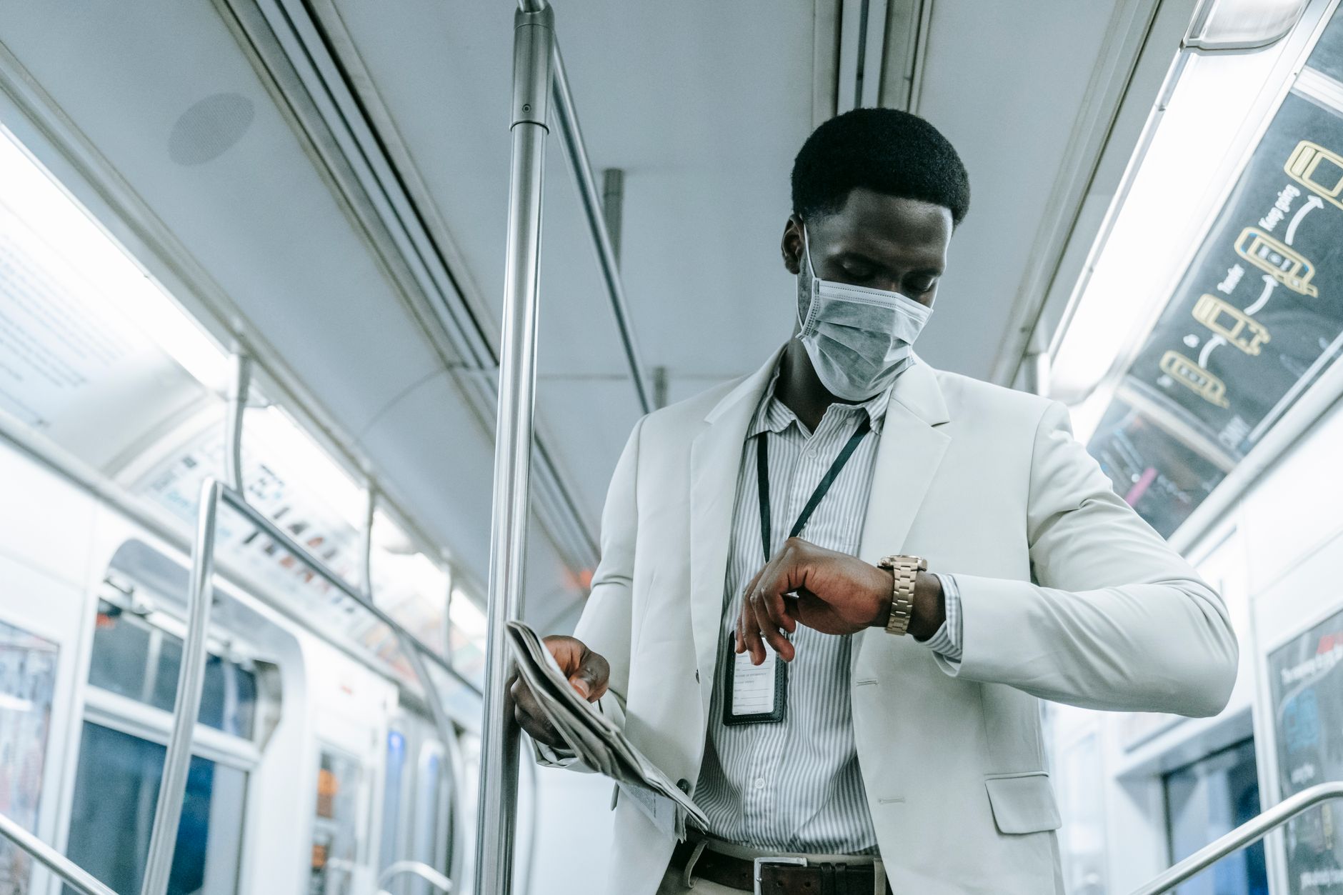 Business professional in mask checking time on subway, reflecting pandemic travel norms.