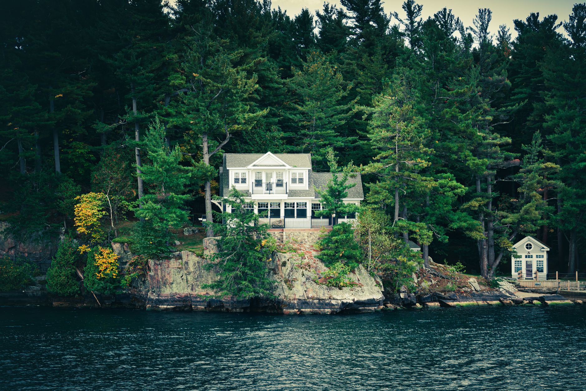 Serene lakefront house nestled among lush trees, ideal for retreat.
