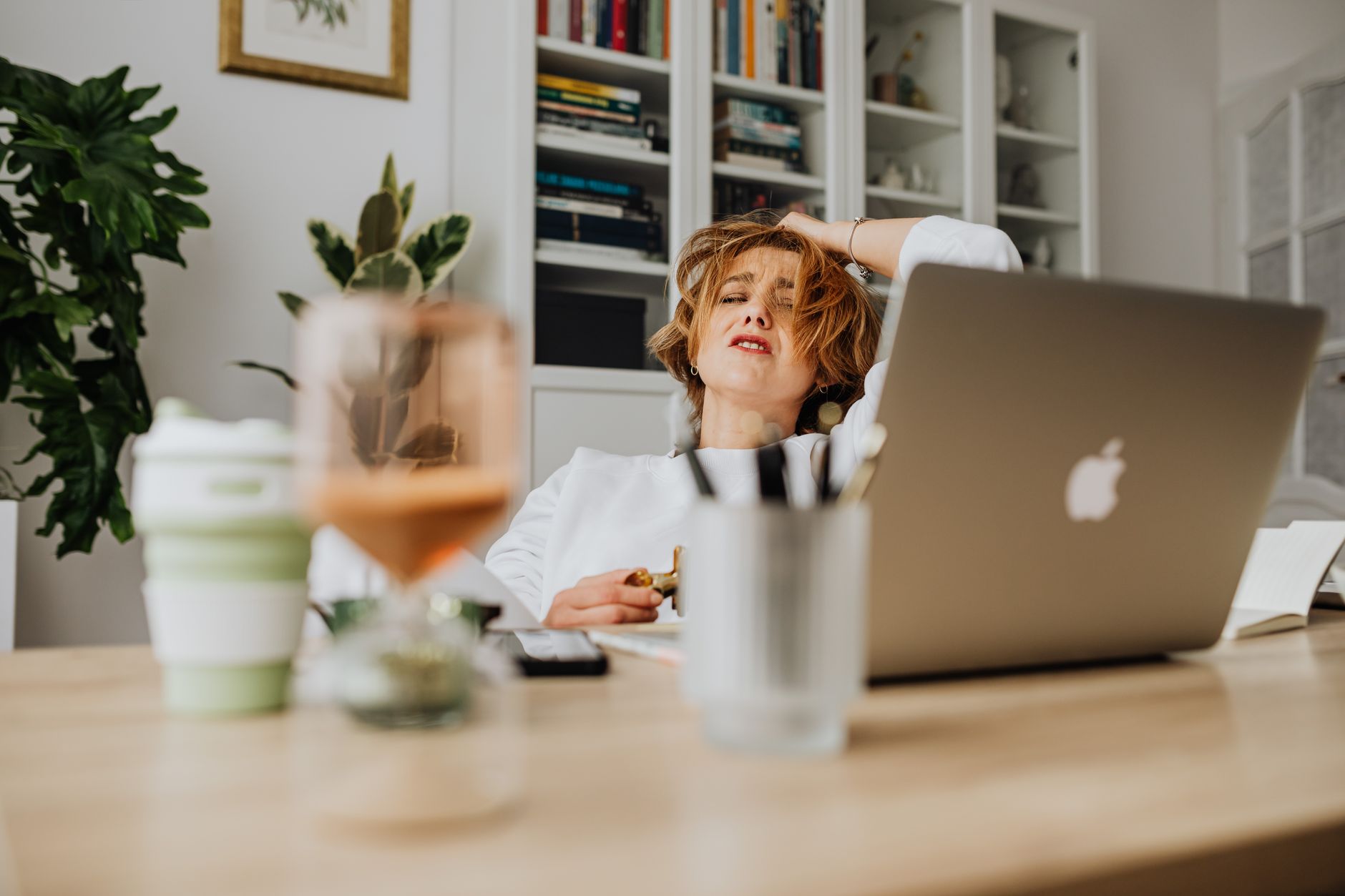 Woman feeling stressed while working from home at a desk with a laptop.