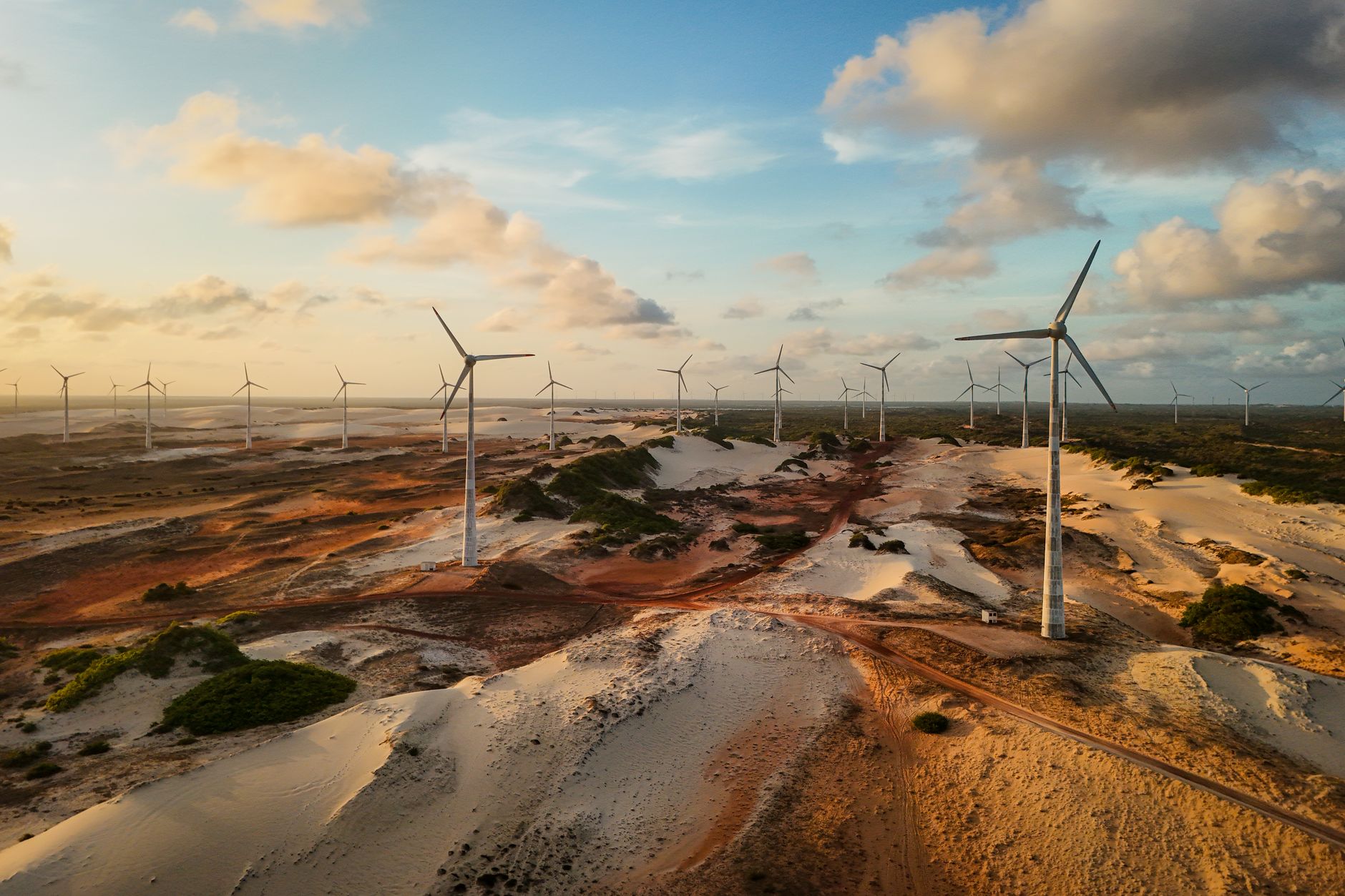 Aerial shot of wind turbines in a sprawling desert at sunset, capturing renewable energy.