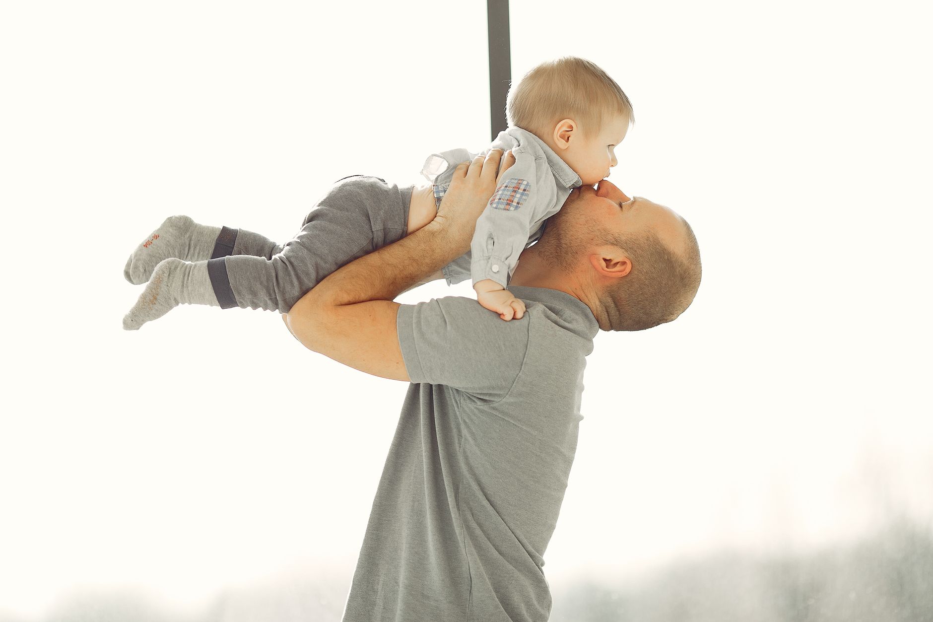 A father lovingly lifts his baby, showcasing a tender parent-child bond.
