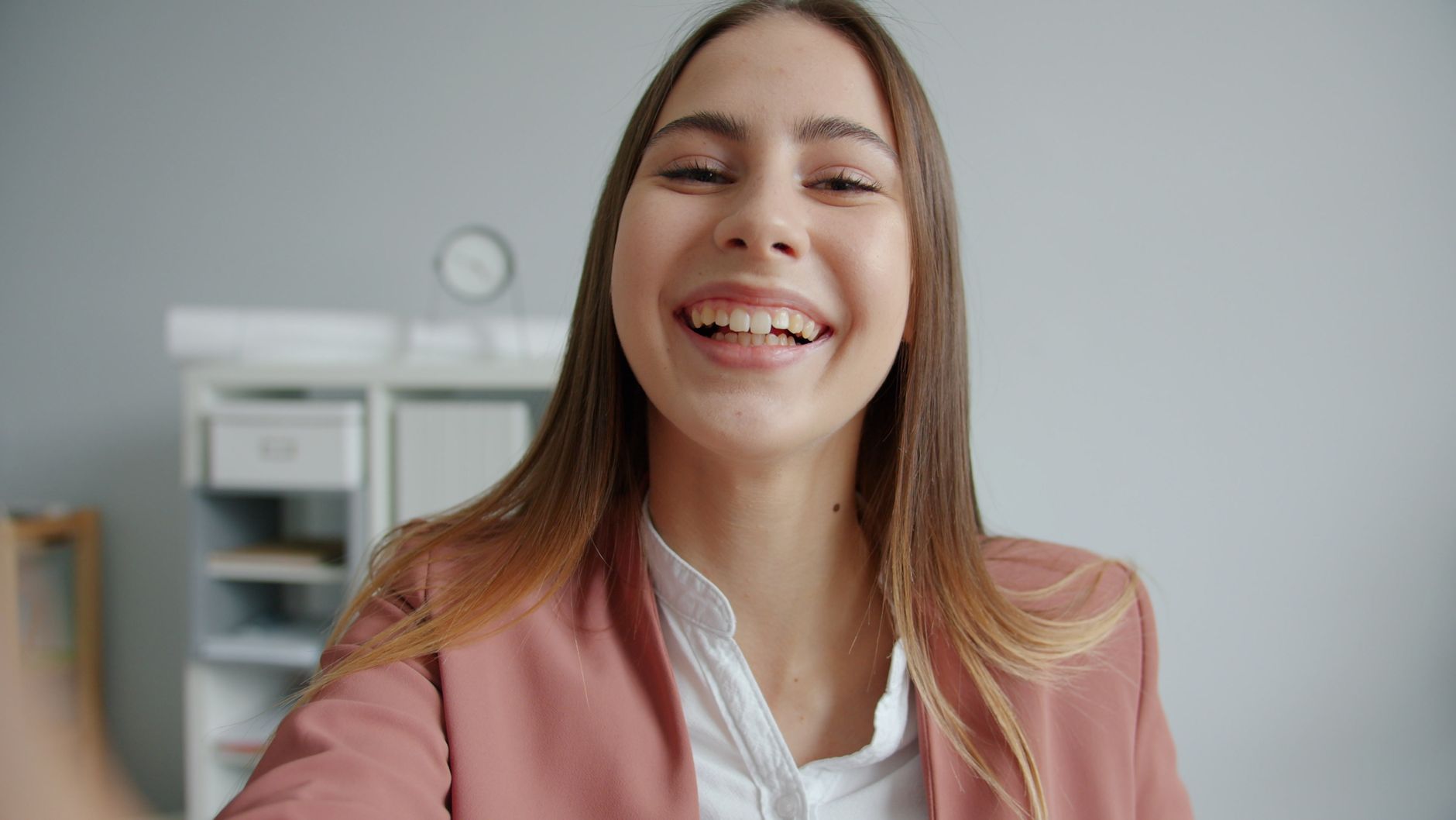 A joyful young woman in an office setting showing positive emotions while wearing business attire.