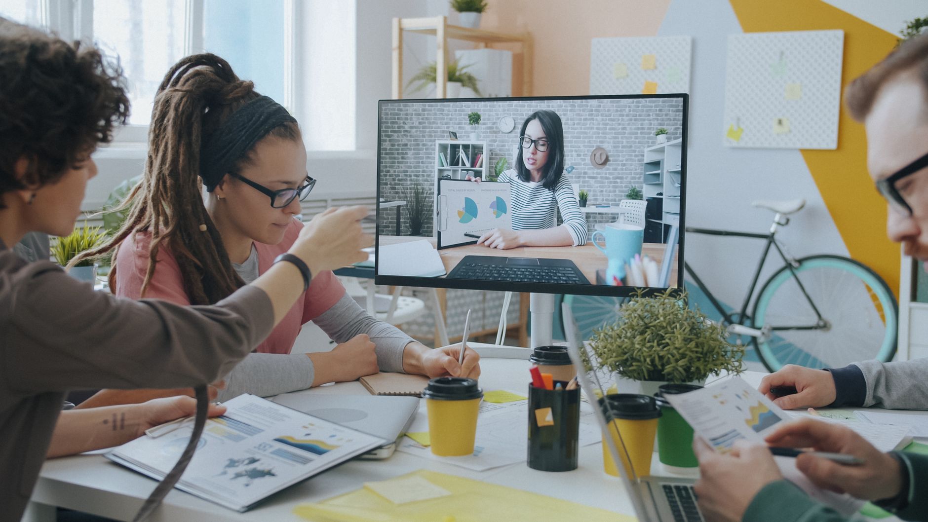 Young professionals collaborate during a video call in a creative and modern office setting.
