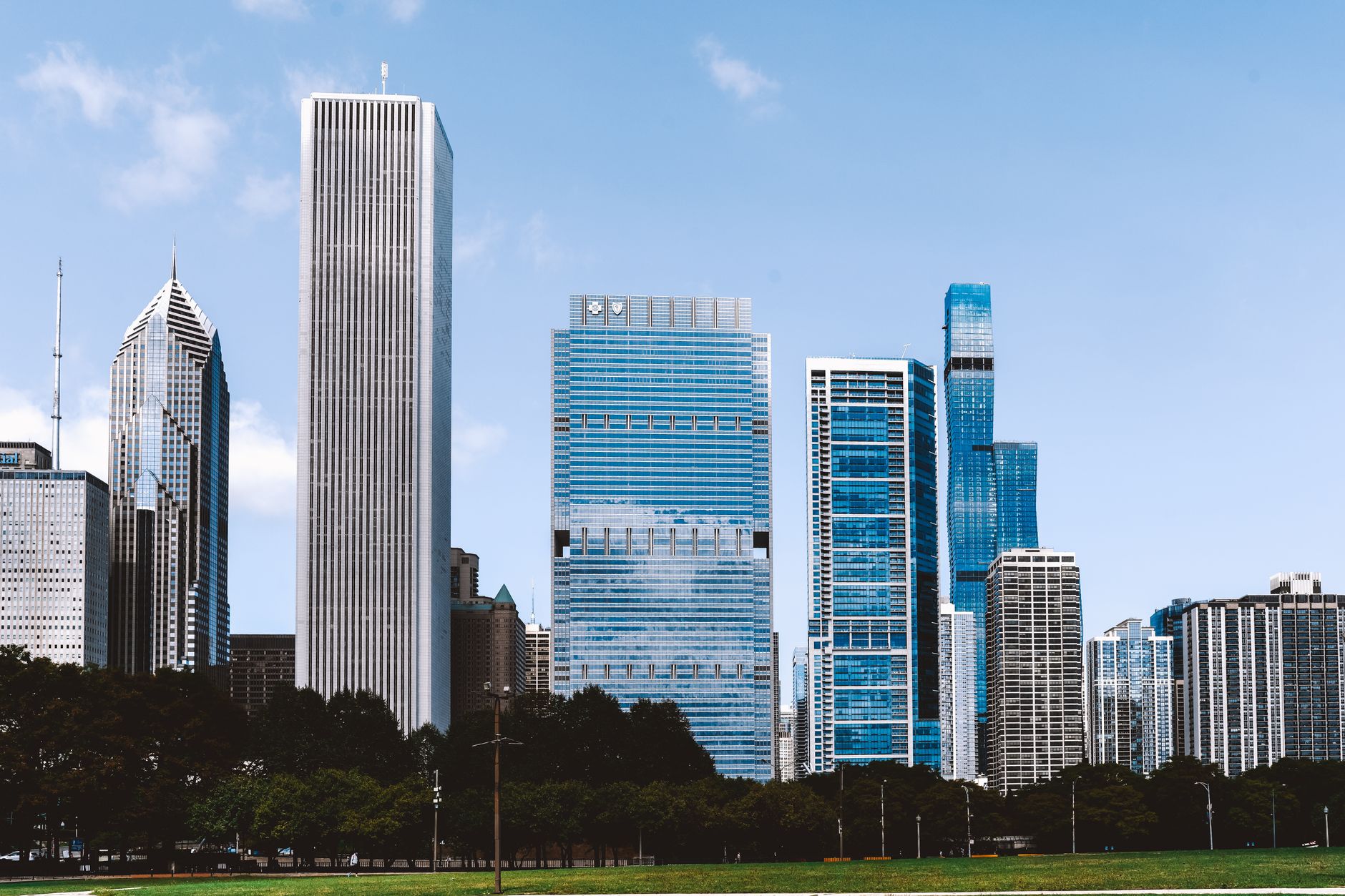 Scenery of modern glass skyscrapers of Chicago city surrounded with lush green park under blue sky