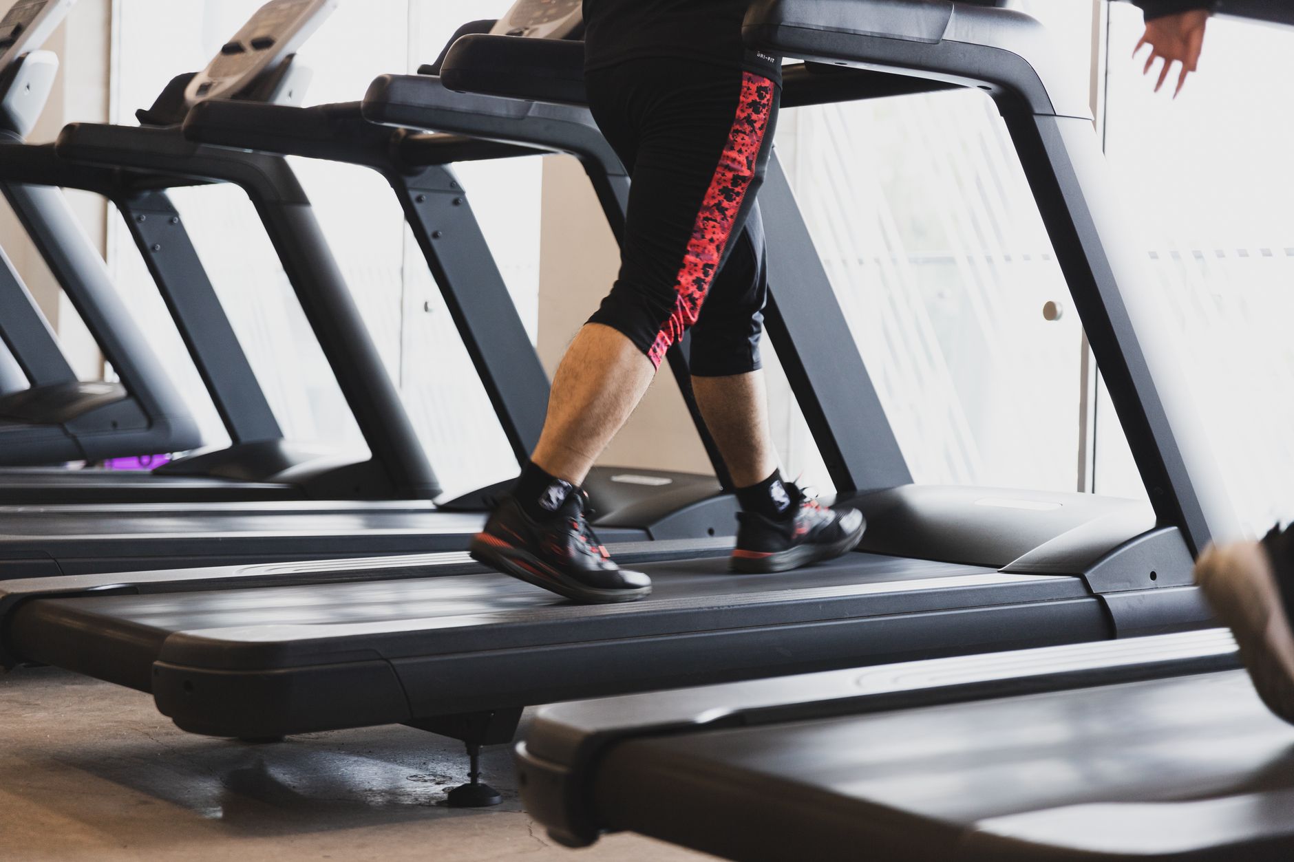 A person walking on a treadmill in a modern gym setting, focusing on fitness.