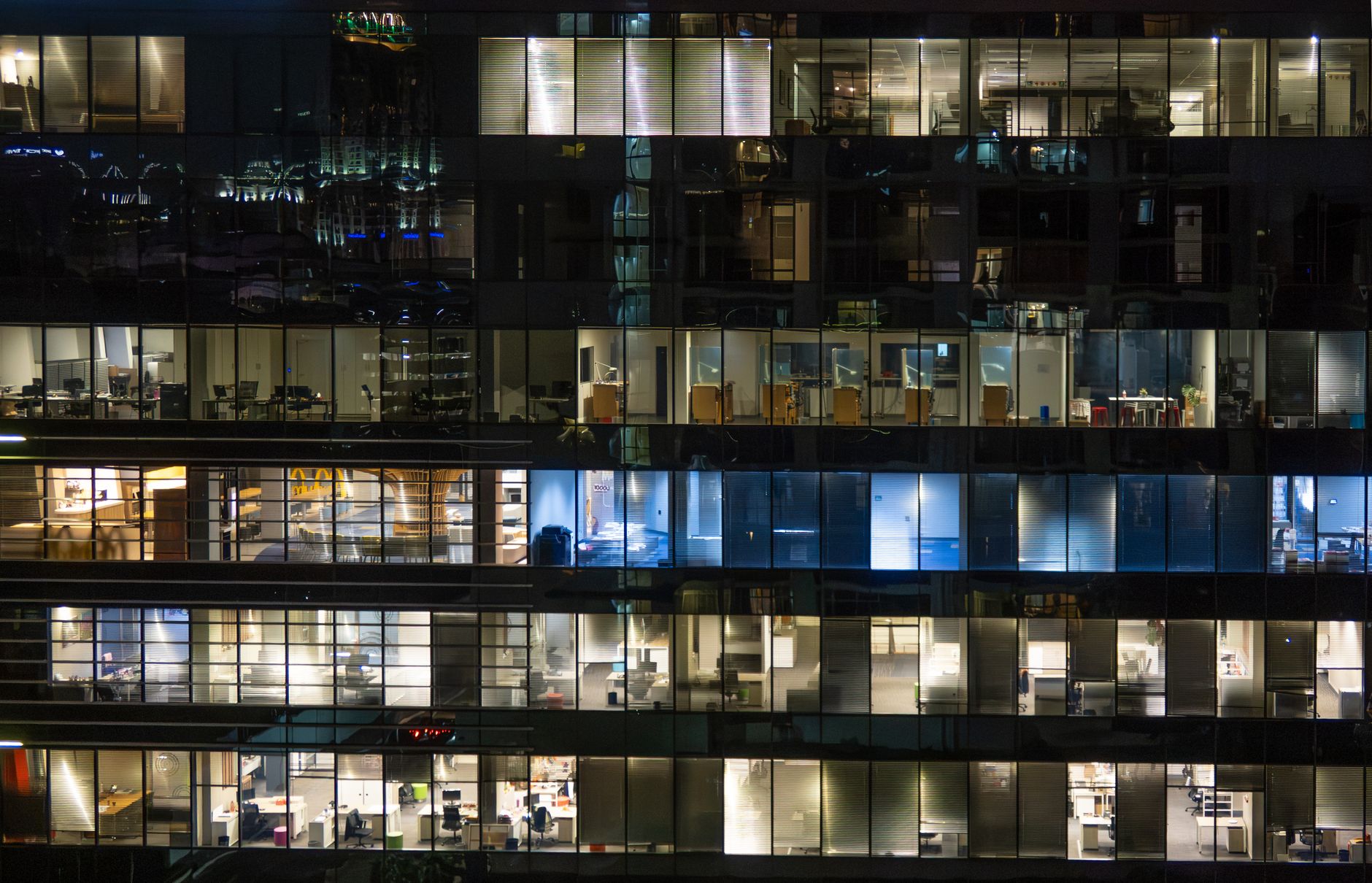View of a city office building at night with illuminated floors showcasing modern architecture.